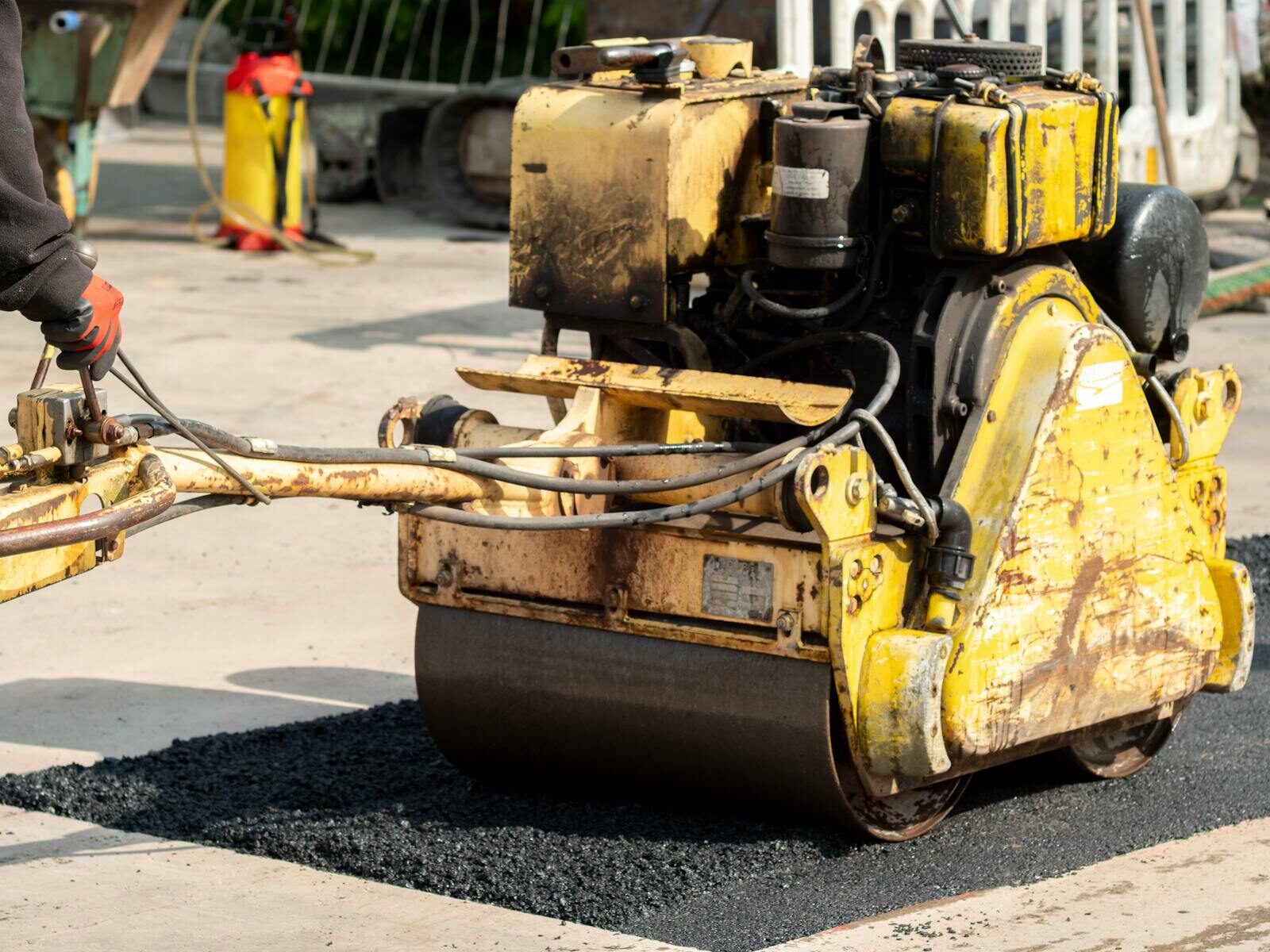 Pedestrian roller compacting hot-mix patch on saw-cut