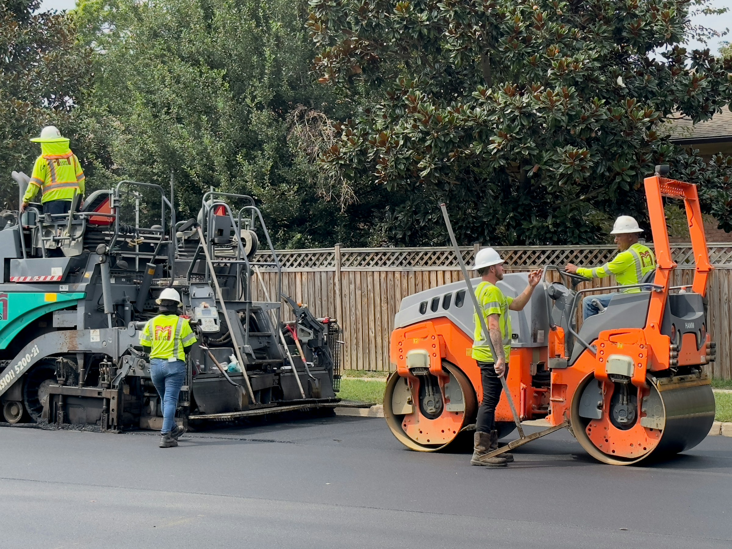 Asphalt resurfacing crew with paver and roller laying fresh AC10 hot-mix overlay