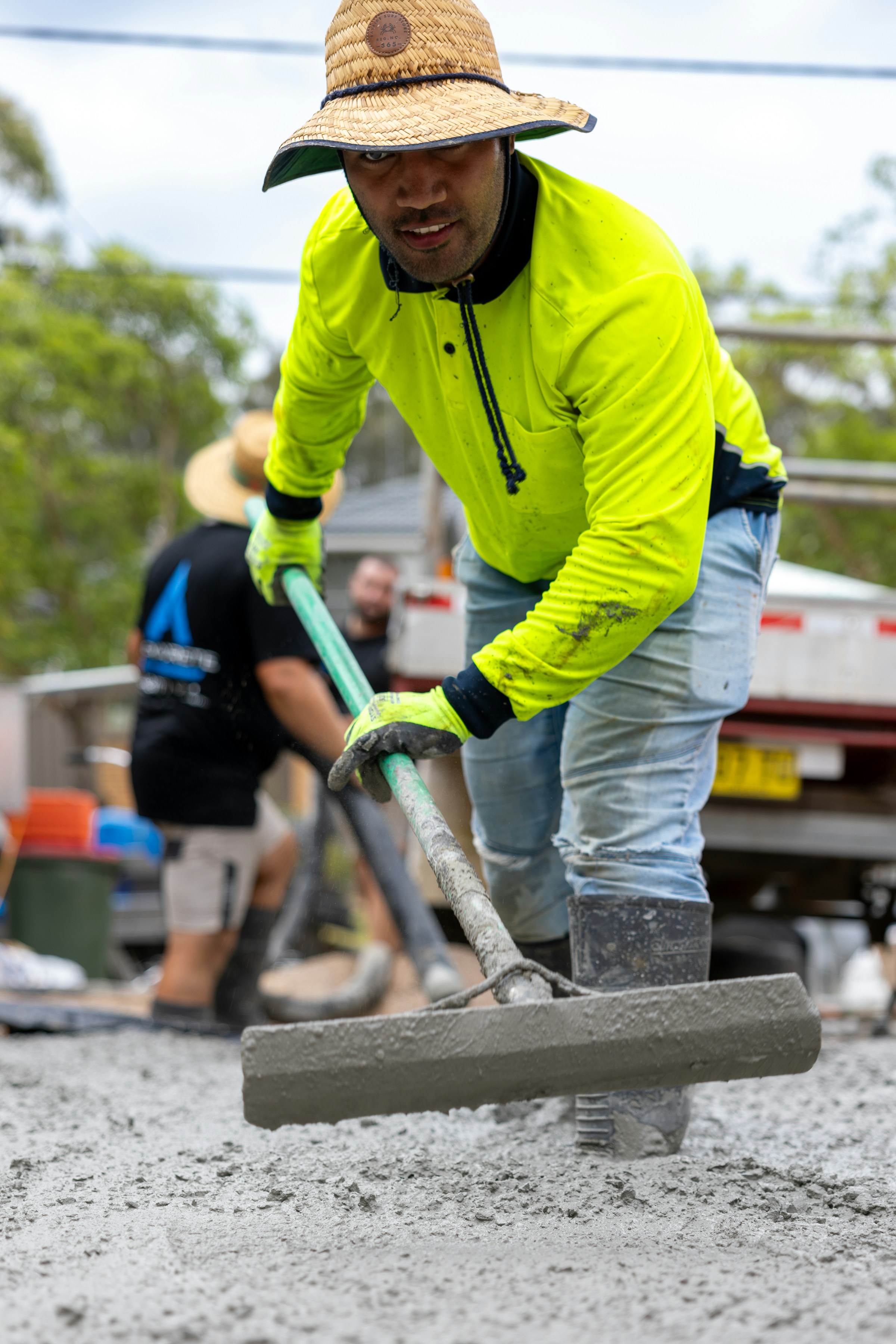 Concrete crew screeding fresh wet concrete on a driveway crossover, Central Coast NSW