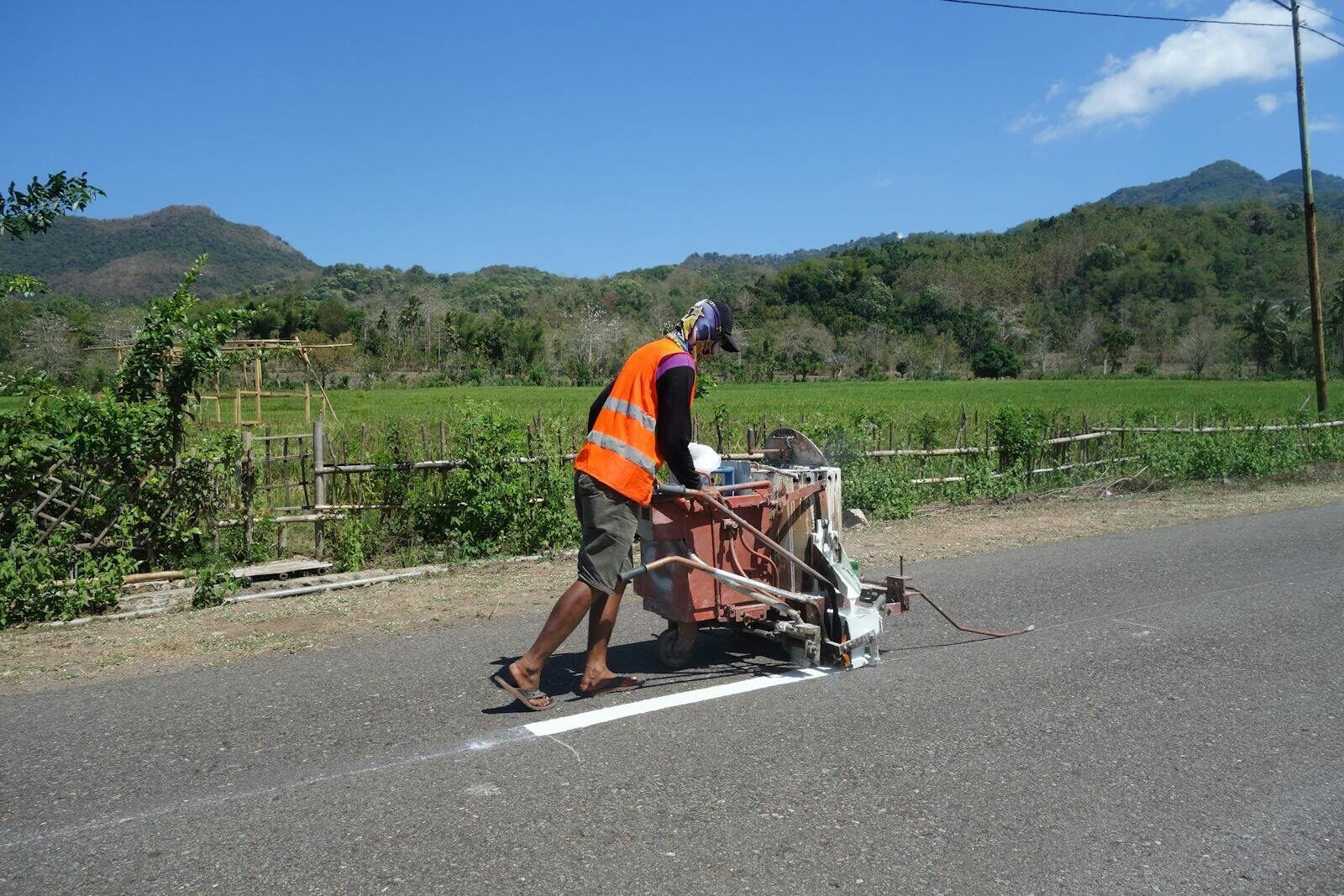 Crew operating a road-marking machine painting yellow line