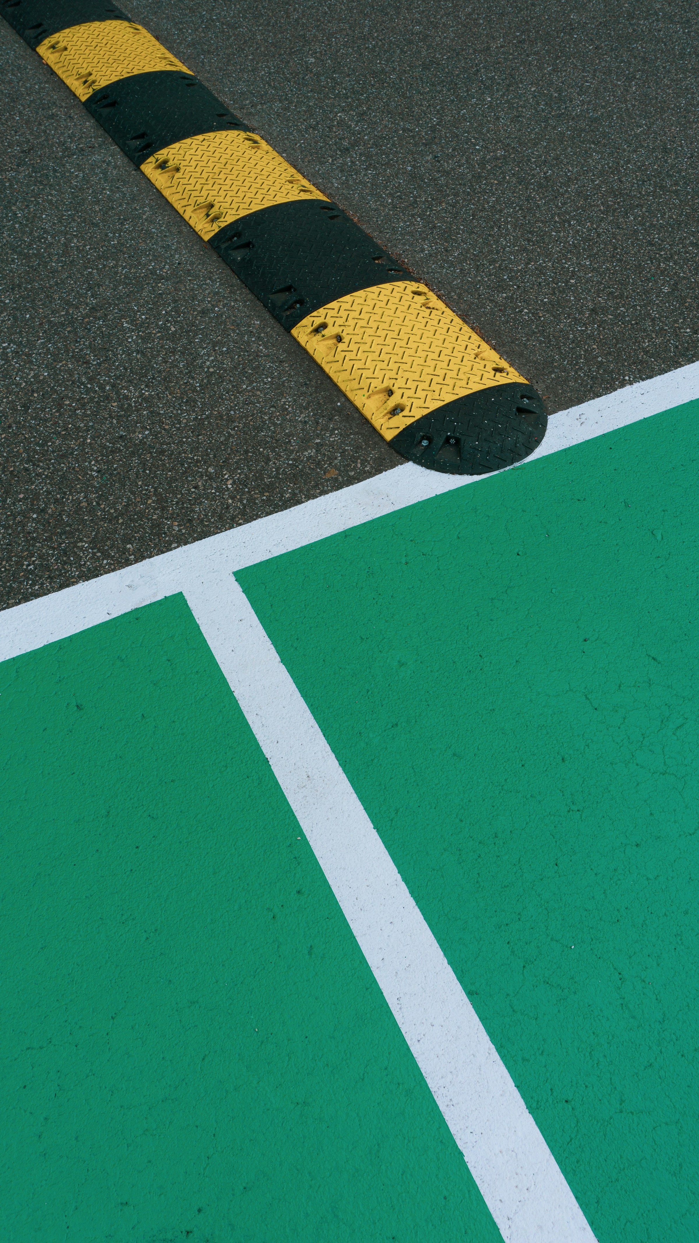Rubber speed hump alongside painted line marking on asphalt β traffic calming + carpark marking combined