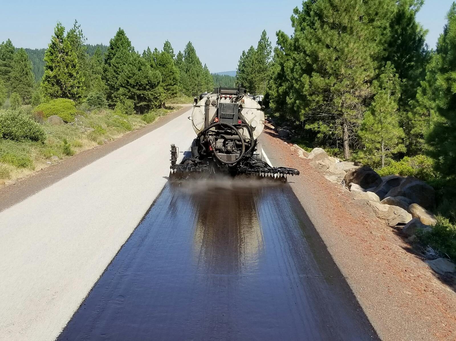 Distributor laying down dark bitumen seal coat